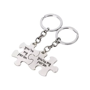 May include: Two silver keychains with interlocking puzzle pieces that say "you're my person".
