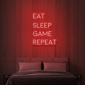 Könnte beinhalten: Rotes Neon-Schild mit weißem Text "Eat Sleep Game Repeat" an einer dunklen Holzwand montiert, über einem Bett mit zwei Kissen.