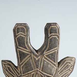 May include: Close-up of a wooden giraffe sculpture with a geometric pattern carved into the surface. The sculpture is painted in shades of brown and black.