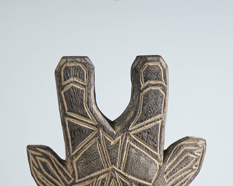 May include: Close-up of a wooden giraffe sculpture with a geometric pattern carved into the surface. The sculpture is painted in shades of brown and black.
