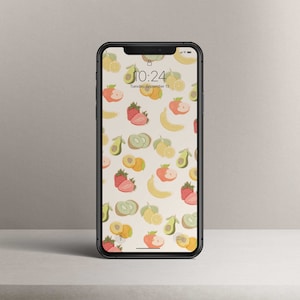 Könnte beinhalten: Ein Smartphone mit weißem Hintergrund und einem Muster aus verschiedenen Früchten, darunter Erdbeeren, Bananen, Zitronen, Avocados und Kiwis. Die Uhrzeit ist 10:24 Uhr und das Datum ist Dienstag, der 13. September.
