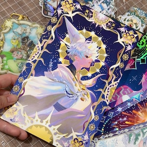May include: A collection of fantasy art prints featuring a character in a white robe and hat, set against a starry night sky. The prints have gold foil accents and intricate border designs. Other decorative items are also visible.