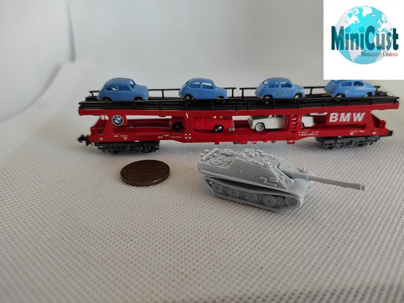 Puede incluir: Un vag&oacute;n de tren rojo de juguete con un tanque gris sobre una superficie blanca. El vag&oacute;n lleva cuatro coches de juguete azules y tiene la palabra "BMW" impresa en el lateral.