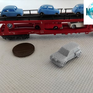 Puede incluir: Un vag&oacute;n de tren de juguete rojo con una plataforma que transporta tres coches de juguete azules. El vag&oacute;n de tren tiene un logotipo de BMW en el lateral. Un coche de juguete gris est&aacute; sentado en una superficie blanca delante del vag&oacute;n de tren.