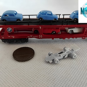 Puede incluir: Un vag&oacute;n de tren rojo de juguete con un logotipo BMW azul y tres coches de juguete azules en una plataforma. El vag&oacute;n de tren tiene el texto "THE MA 133061" impreso en el lateral. Un coche de carreras blanco de juguete est&aacute; sobre una superficie blanca.