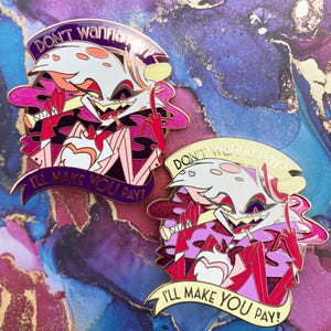Op de afbeelding: Twee emaille pins met een cartoonfiguur met een wit gezicht, roze accenten en een rode middelvinger. De pins hebben de tekst "DON'T wanna pay?" en "I'LL MAKE YOU PAY!" op banners. De pins hebben een gouden omtrek.