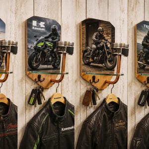 Può includere: Portachiavi e attaccapanni a tema motociclistico. Ogni espositore in legno presenta un'immagine di moto, un ripiano in vetro e ganci per chiavi e giacche. Le giacche sono in pelle nera con loghi di marchi motociclistici.