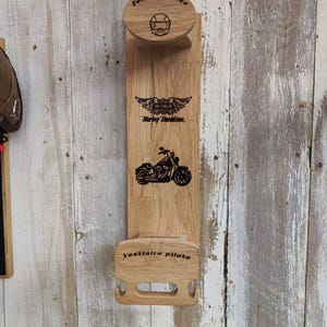 Può includere: Porta casco e giacca da moto in legno con logo Harley-Davidson inciso e grafica motociclistica. Presenta il testo "Zone Réservée" e "Vestiaire pilote". Il supporto è montato su uno sfondo in legno rustico e usurato.