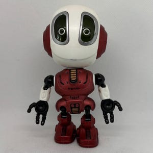 Op de afbeelding: Een rode en witte speelgoedrobot met een rond hoofd en grote ogen. De robot heeft de woorden "Metal Robot" op zijn borst.