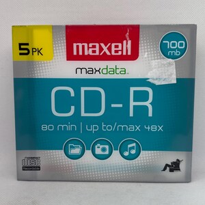 May include: A package of five Maxell CD-R discs. The box is teal and gray with the text "CD-R" in large white letters. It also features the text "maxell maxdata" and icons for a file folder, camera, and musical note.