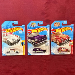 May include: Three Hot Wheels die-cast model cars on their original packaging. The cars are a white Volkswagen Beetle, a purple Custom '59 Volkswagen Squareback, and a red Volkswagen Beetle. Each car is on a blue and white card.