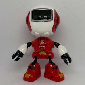 Op de afbeelding: Een rood en wit robot speelgoed met een zwart scherm op zijn hoofd. De robot heeft het woord "BOXY" op zijn borst.