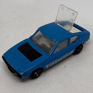 May include: A vintage blue toy car with a clear plastic roof panel. The car has black accents and the word "BAGHEERA" printed on the side. The toy car is a die-cast model.