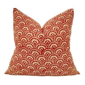 May include: Red and cream throw pillow with a geometric pattern of overlapping semi-circles.