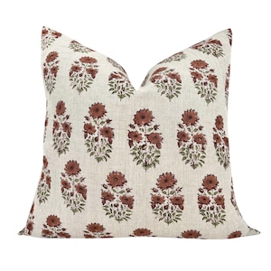 May include: A square throw pillow featuring a light beige, textured fabric base with a repeating pattern of small, dark reddish-brown flowers and green leaves arranged in vertical columns across the entire surface of the pillow cover.