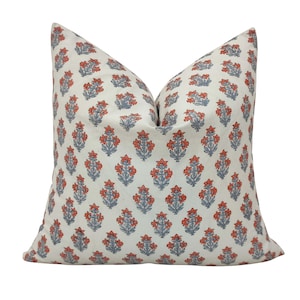 Puede incluir: Una almohada blanca con un patrón floral en tonos azules y coral. La almohada está hecha de una tela de algodón suave y tiene un brillo sutil.