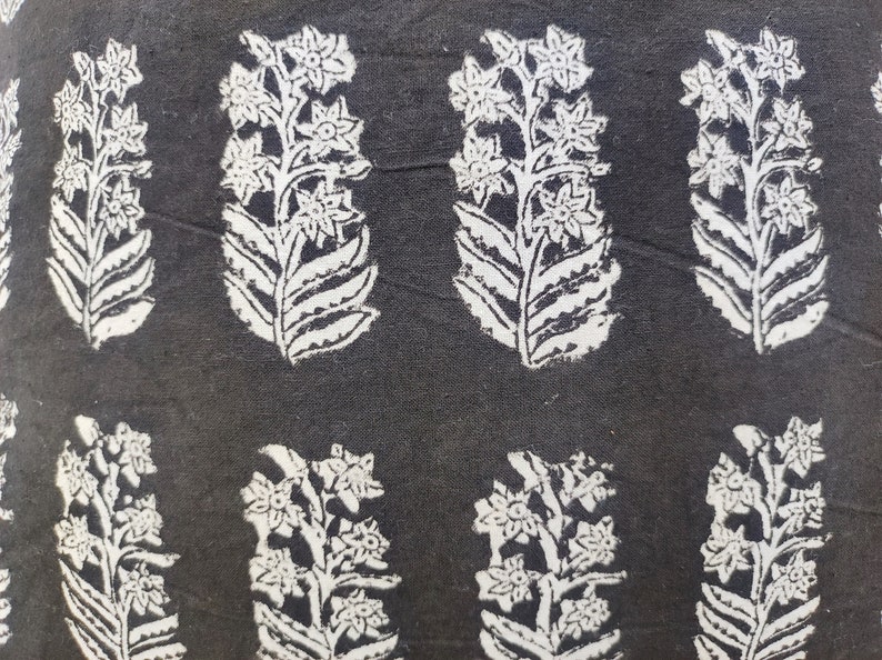 Pu&ograve; includere: Tessuto nero con un motivo floreale bianco. Il motivo presenta un disegno ripetitivo di fiori stilizzati con foglie.