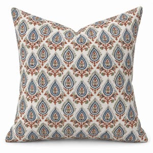 May include: A square throw pillow featuring an off-white background with a repeating pattern of stylized teardrop-shaped floral motifs in shades of navy blue, terracotta orange, and sage green, arranged in a symmetrical grid across the fabric.