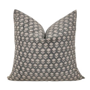 Può includere: Un cuscino grigio e bianco con motivo floreale e bordo smerlato.