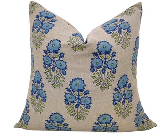 May include: A decorative throw pillow with a floral pattern. The pillow is made of a light beige linen fabric and features a repeating pattern of blue and green flowers.