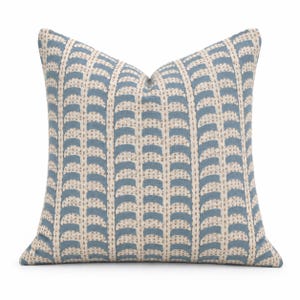 May include: A square throw cushion featuring a repeating pattern of vertical columns of blue semi-circular shapes on a light beige background. The design includes thin, dotted vertical lines separating each column of blue arches across the fabric.