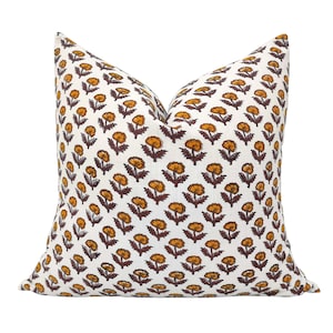 May include: A white pillow cover with a repeating pattern of small orange flowers with brown stems on a white background.