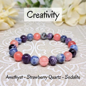 Puede incluir: Un brazalete hecho con cuentas de amatista, cuarzo fresa y sodalita. El brazalete está sobre un fondo blanco con la palabra "Creatividad" encima. El brazalete está hecho con cuentas de 8 mm.
