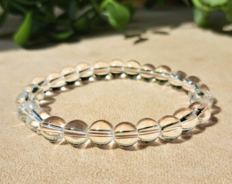 Peut inclure: Un bracelet en perles de cristal de roche clair. Le bracelet est composé de perles rondes et lisses qui sont enfilées sur un cordon élastique transparent.