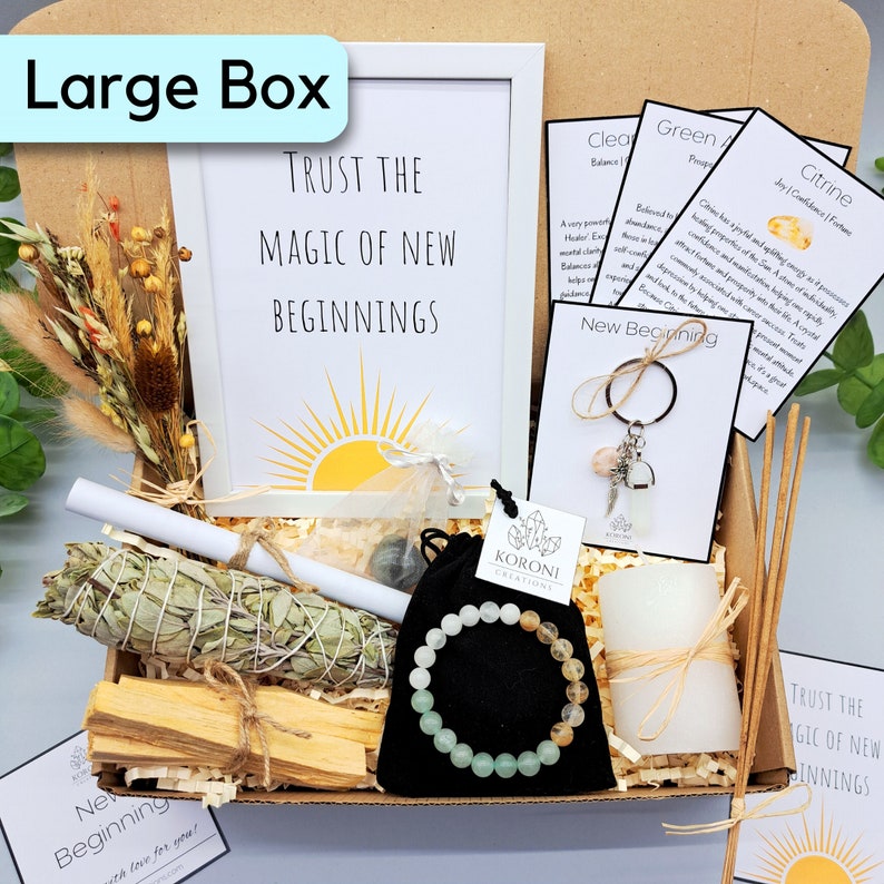May include: A large box filled with spiritual items. Includes a framed print with the text "Trust the Magic of New Beginnings", a sage bundle, palo santo sticks, a bracelet, a candle, and cards with text.