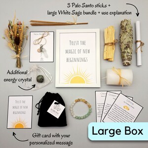 May include: A collection of spiritual items including Palo Santo sticks, a white sage bundle, a framed print with the text "Trust the Magic of New Beginnings", a bracelet, and a gift card. The items are arranged on a light gray surface.