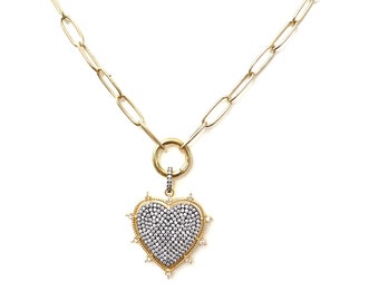 May include: A gold chain necklace with a large, heart-shaped pendant. The pendant is covered in small, clear stones and has a gold border.