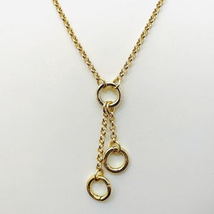 May include: A gold chain necklace with a dangling charm featuring three connected circles.