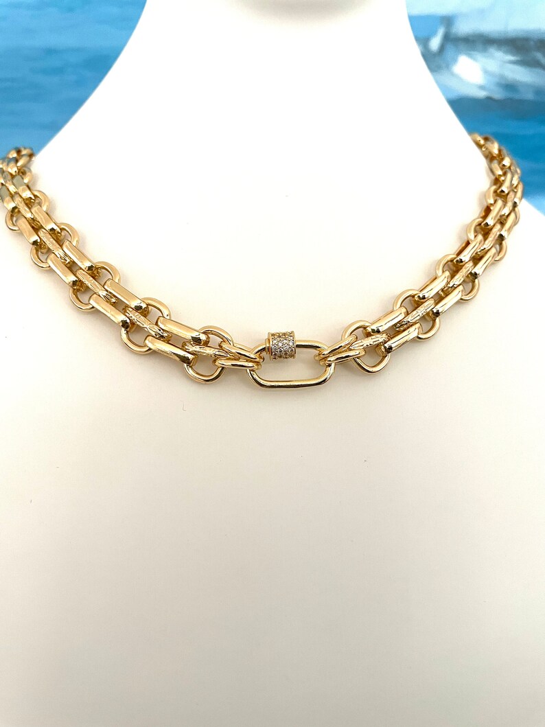 May include: A gold chain necklace with a double row of linked chain links and a small, round, pave-set clasp.