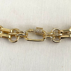 May include: Gold chain necklace with a chunky link design and a small, clear crystal-encrusted clasp.
