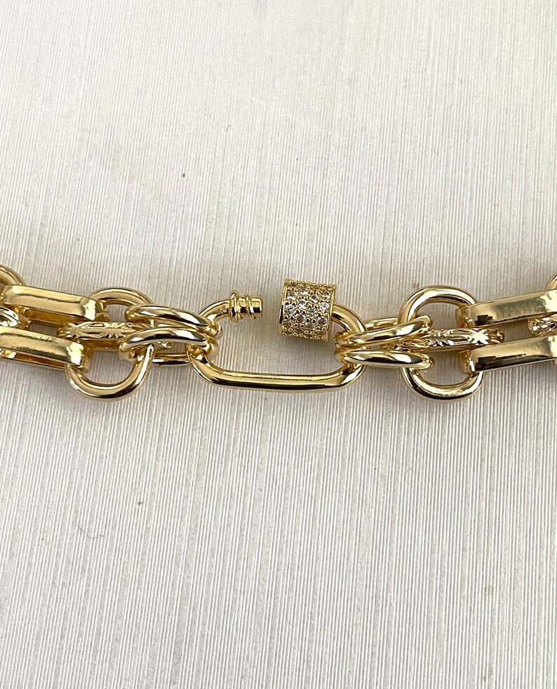 May include: Gold chain necklace with a chunky link design and a small, clear crystal-encrusted clasp.