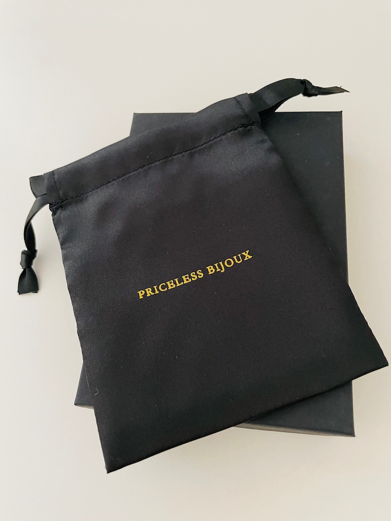 May include: A black satin drawstring bag with the text "PRICELESS BIJOUX" printed in gold.