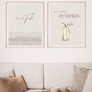 May include: Two framed prints with fall-themed designs. The left print features a field of wheat with the text "Hello Fall". The right print features a white pumpkin with the text "Hey There Pumpkin".