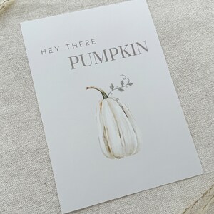 May include: A white printable sign with the text "Hey there pumpkin" in gray text. A watercolor illustration of a white pumpkin with a green stem and leaves is below the text.