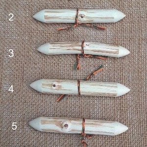 May include: Six wooden knitting needles with orange and green string tied around the middle of each needle. The needles are numbered 1 through 6.