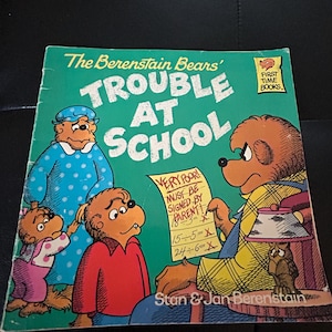 May include: A vintage copy of "The Berenstain Bears' Trouble at School" book. The cover features illustrations of bear characters and the title in large, bold letters. The book has a green cover with the text "VERY POOR! MUST BE SIGNED BY PARENT" on a green paper.