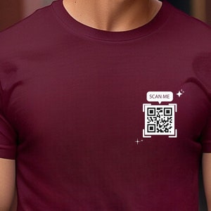 Peut inclure: Un t-shirt bordeaux avec un code QR blanc et le texte "SCAN ME" dans une bulle de dialogue.