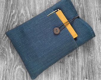 May include: A dark blue linen pouch with a brown button closure. A yellow notebook is tucked inside the pouch.