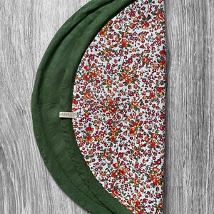 May include: A green and white round tablecloth with a floral pattern. The tablecloth has a green border and a label that says "Lasgallet".