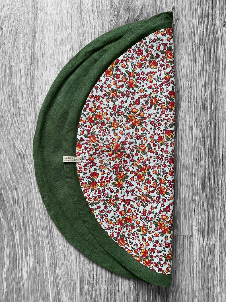 May include: A green and white round tablecloth with a floral pattern. The tablecloth has a green border and a label that says "Lasgallet".