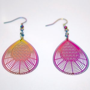 May include: A pair of iridescent teardrop-shaped earrings with a delicate, intricate design. The earrings are made of metal and have a rainbow finish.