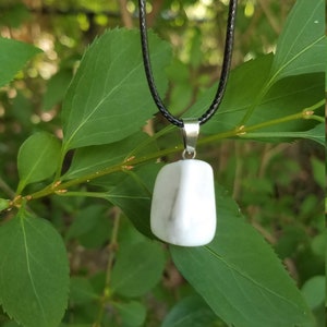 May include: A white stone pendant on a black cord necklace. The pendant is a smooth, rounded rectangle shape.