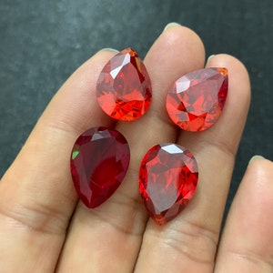 May include: Four teardrop-shaped red crystal beads with a faceted design.