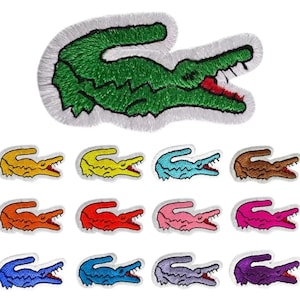 May include: Embroidered patches featuring a crocodile design in various colors. The top patch is green with a red mouth and white border. Below are patches in yellow, blue, brown, orange, red, pink, purple, and other shades.