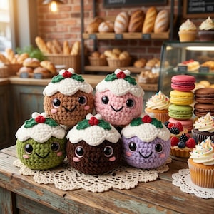 May include: Five round, crocheted plush toys shaped like Christmas puddings in brown, pink, green, dark brown, and purple. Each features a white crocheted topping, green leaves, and red berries, with large black eyes and a stitched smiling mouth.