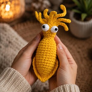 Mostro giallo di peluche all'uncinetto, stravagante creatura dal corpo allungato con grandi occhi e tentacoli di filato, simpatico giocattolo amigurumi, divertente regalo decorativo per la scrivania fatto a mano